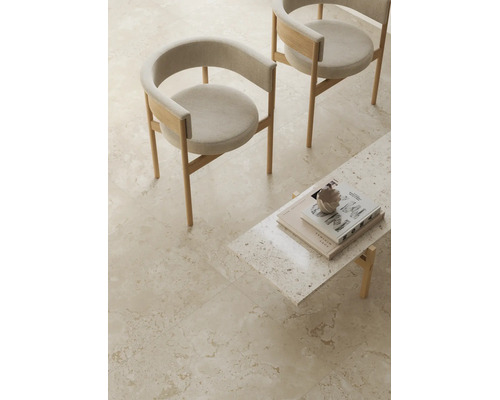 Sol carrelé clair aspect pierre naturelle dans un espace de vie minimaliste avec deux chaises et une petite table.