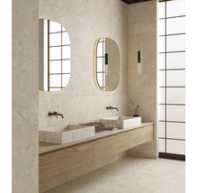 Salle de bain moderne avec double vasque, deux vasques à poser en pierre, robinetterie murale et deux miroirs ovales éclairés sur un mur en pierre.