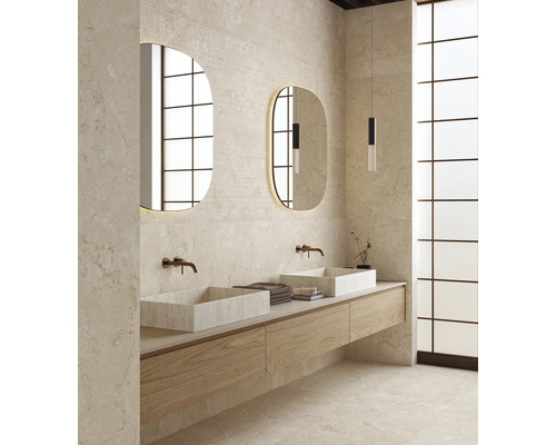 Salle de bain moderne avec double vasque, deux vasques à poser en pierre, robinetterie murale et deux miroirs ovales éclairés sur un mur en pierre.
