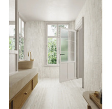 Helles, modern gestaltetes Badezimmer mit Wand- und Bodenfliesen in Natursteinoptik, einem Waschtisch aus Holz und einem Fenster mit Tür.