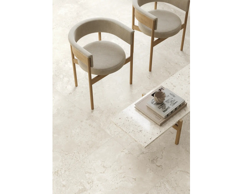 Espace de vie avec chaises modernes en bois et table basse sur carrelage grand format aspect pierre naturelle dans une ambiance minimaliste.