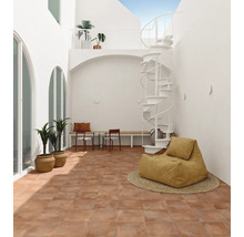 Cour intérieure lumineuse avec carrelage en terre cuite, escalier en colimaçon blanc, banc et pouf dans un design minimaliste et moderne.