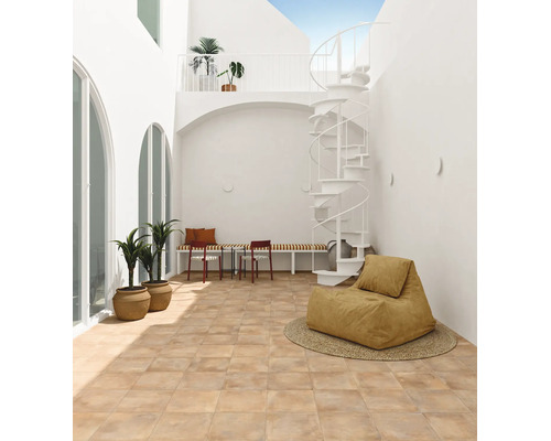 Cour intérieure lumineuse avec sol carrelé, escalier en colimaçon blanc et sièges dans une architecture moderne.