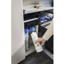 Une main remplace le filtre à eau dans un système d eau Blanco avec bouteille de gaz carbonique dans une armoire de cuisine.