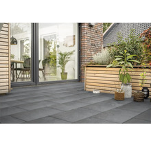 Moderne Terrasse mit grossformatigen Plattenbelag aus Feinsteinzeug, angrenzend an eine Holzfassade mit Hochbeet und raumhoher Verglasung.