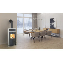 Poêle moderne avec un feu allumé dans un salon devant une fenêtre donnant sur un paysage hivernal enneigé.