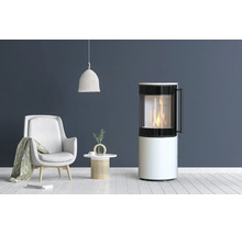 Poêle à bois moderne de forme cylindrique avec vitre et feu ardent dans un salon, à côté d'un fauteuil et d'une table d'appoint.