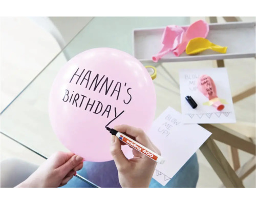 Une personne écrit sur un ballon avec un marqueur permanent Edding 400 pour une fête d anniversaire.