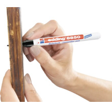Eine Hand nutzt einen Edding 8850 Bohrlochmarker zum Markieren an einer Holzleiste.