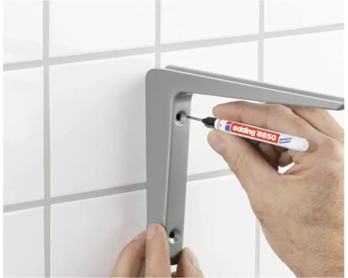 Eine Person markiert mit einem Edding 8850 Spezialmarker die Bohrlöcher für einen Wandregalträger an einer gefliesten Wand.