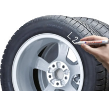 Une main marque un pneu de voiture avec un marqueur pour pneus Edding 8050.