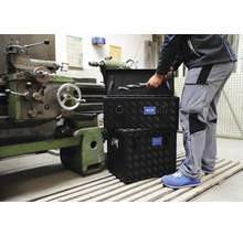 Handwerker mit Alutec Werkzeugkiste aus Aluminium Riffelblech in einer Werkstatt neben einer Drehmaschine.