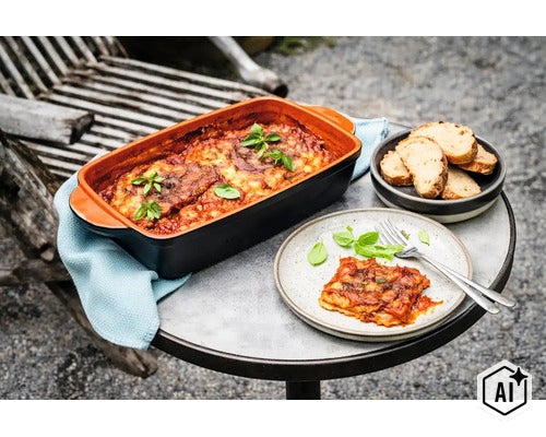 Eine rechteckige Keramik Auflaufform mit frisch zubereiteter Lasagne auf einem runden Tisch mit Teller, Brot und Besteck. (Image AI modified or generated)