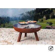 Runde Feuerschale aus Metall mit Grillrost und Kochgeschirr auf einer Terrasse mit Alpenpanorama im Hintergrund. (Image AI modified or generated)