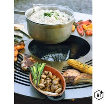 Feuerstelle mit Grillplatte, auf der Fleisch, Maiskolben und Pilze zubereitet werden, darüber ein Kochtopf mit Reis. (Image AI modified or generated)