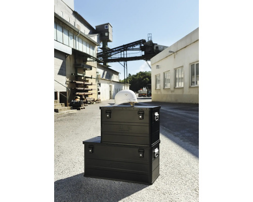 Zwei schwarze Aluminium Transportboxen von Alutec mit einem Bauhelm auf dem Werksgelände im Freien.