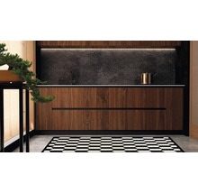 Moderne Kuche mit Holzfronten, dunkler Steinruckwand, Armatur und Kochtopf sowie einem grafisch gemusterten Teppich auf dem Boden.