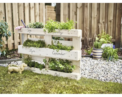 Holzpaletten Kräuterregal für den Garten mit beschrifteten Fächern für verschiedene Kräuterarten.