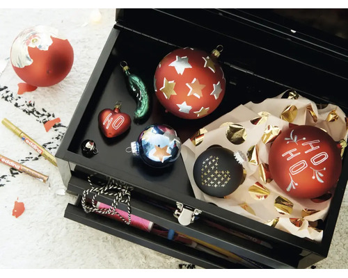 Une boîte à outils noire ouverte contenant plusieurs boules de Noël décoratives et deux marqueurs Edding pour la décoration.