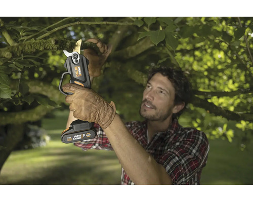 Un jardinier coupe une branche avec un sécateur sans fil Worx Nitro dans un jardin.