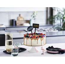 Gâteau décoré de baies et de panneaux avec inscription Salted Caramel sur un présentoir dans une cuisine moderne