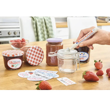 Stylo dissolvant d'étiquettes Edding 8180 utilisé pour enlever les résidus de colle d'un pot vide, entouré de pots de confiture et de fraises.