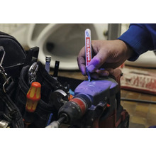 Une main marque un marteau perforateur avec un marqueur de sécurité Edding 8280 utilisant de l encre ultraviolette pour la protection antivol