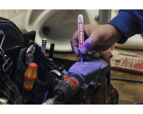 Une main marque un marteau perforateur avec un marqueur de sécurité Edding 8280 utilisant de l encre ultraviolette pour la protection antivol