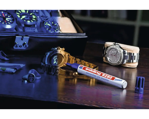 Marqueur UV Edding 8280 Securitas sur une table en bois avec des montres et des bijoux
