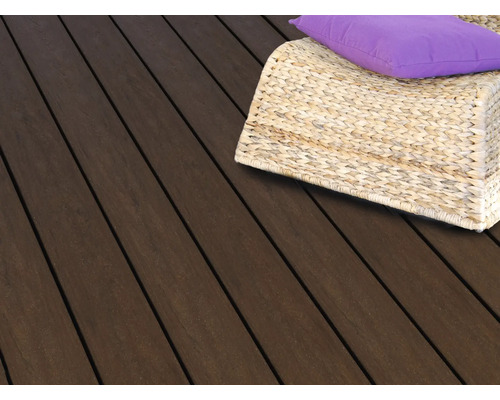 Lames de terrasse en bois foncé avec un fauteuil tressé en osier et un coussin violet sur une terrasse.
