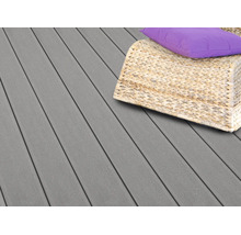 Geriffelte Terrassendielen aus Verbundwerkstoff auf einer Terrasse mit einem Rattanmöbelstück und Kissen.