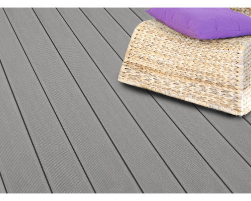Geriffelte Terrassendielen aus Verbundwerkstoff auf einer Terrasse mit einem Rattanmöbelstück und Kissen.