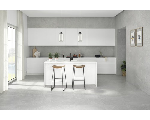 Cuisine claire avec îlot de cuisine, tabourets de bar et carrelage gris au sol.
