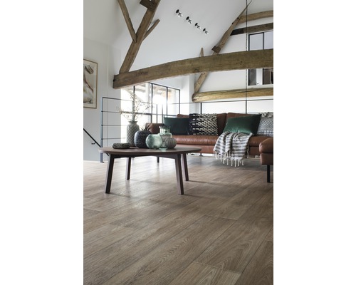 Wohnzimmer mit Holzbalken, braunem Ledersofa, rundem Tisch und Holzboden