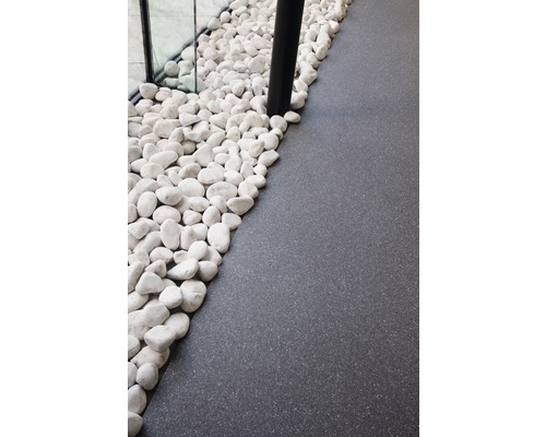 Dekorative weisse Kieselsteine neben dunklem Bodenbelag