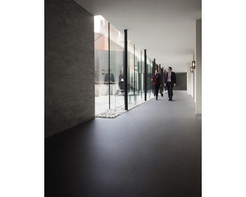 Innenraum mit dunklem Bodenbelag und Glaswand zu einem Außenbereich mit Kies