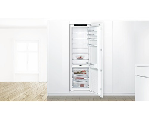 Einbaukühlschrank mit offener Tür und mehreren Regalen zur Lebensmittelaufbewahrung in einer hellen Küche.