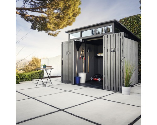 Abri de jardin avec portes ouvertes et outils de jardin dans le jardin.