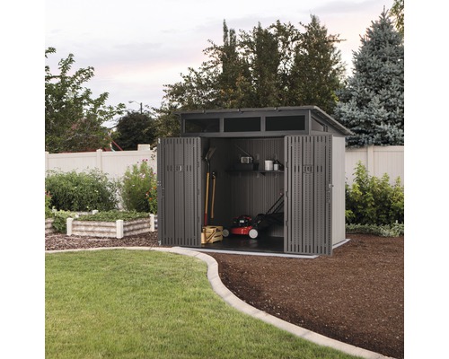 Abri de jardin avec portes ouvertes, tondeuse à gazon et outils de jardinage à l''intérieur.