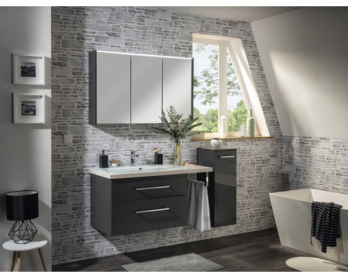 Salle de bains moderne avec meuble sous-lavabo, armoire de toilette, armoire latérale et baignoire devant un mur en pierre