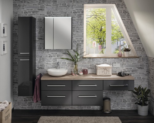 Salle de bains moderne avec lavabo, meuble bas, armoire de toilette à miroir et armoire haute devant un mur en pierre