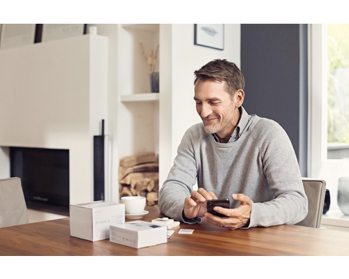 Un homme est assis à table et utilise un smartphone