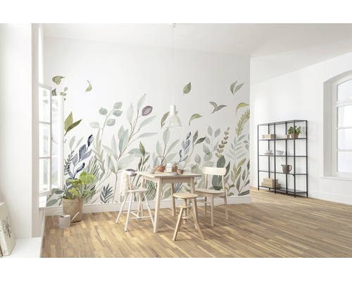 Salle à manger lumineuse avec sticker mural à motif de feuilles, table en bois et chaises