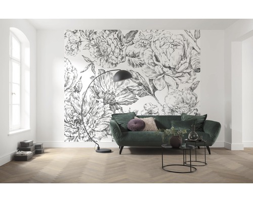 Salon avec papier peint à motif floral, canapé vert et lampadaire