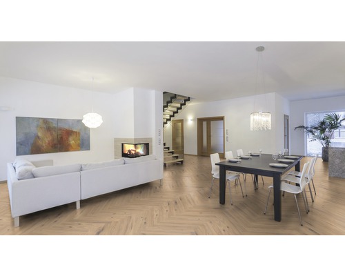 Salon lumineux avec parquet à chevrons, canapé, table à manger et escalier