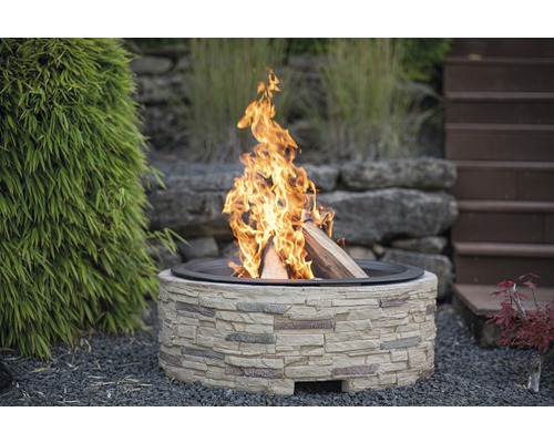 Foyer en pierre avec du bois qui brûle dans le jardin