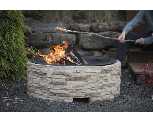 Foyer en pierre avec pain cuit sur un bâton au-dessus du feu