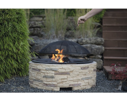 Foyer avec entourage en pierre et grille de protection dans le jardin