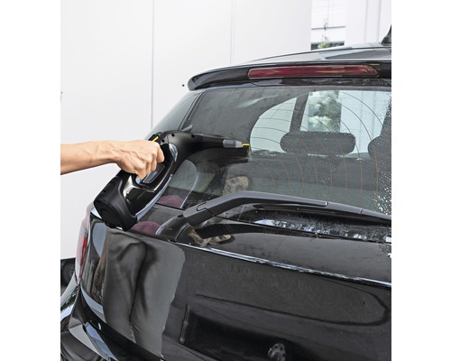 Une personne nettoie la lunette arrière d''une voiture avec un aspirateur de vitres.