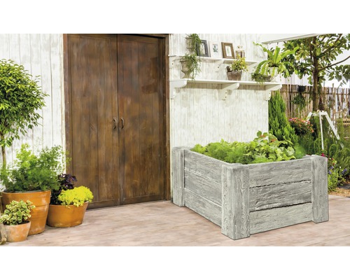 Szene mit Hochbeet, Pflanzen und Gartendekoration vor einer Holztür.